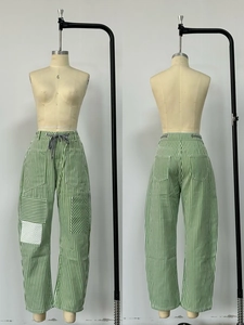 Detailed view of green striped wide-leg pants with utility pockets and drawstring waist