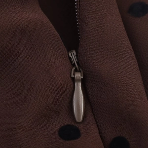 Detailaufnahme des unsichtbaren Reißverschlusses an einem braunen Polka-Dot-Kleid