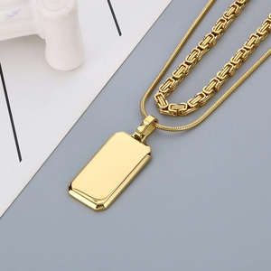 Detailed macro shot of gold double-layer necklace with dog tag pendant on grey background
