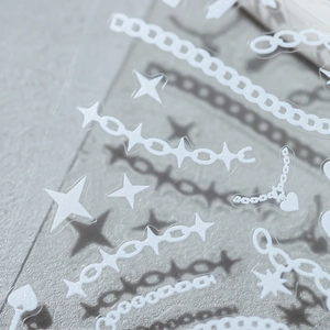 3D embossed white nail stickers with star and chain patterns on a gray stone background
