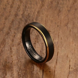 Black brushed 5mm tungsten carbide ring with gold inner plating on wooden surface