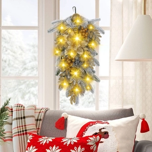 Frosted Christmas teardrop swag with gold ornaments and warm LED lights on a window