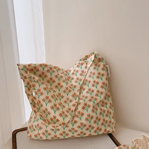 Detail of floral canvas tote bag showing orange buds and simple wish woven label