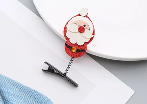 Détail d'une pince à cheveux Père Noël rouge pailletée avec ressort souple et base en métal