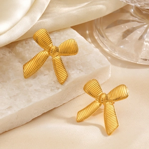 Fashionable 18K gold plated oversized bow earrings on white stone and silk fabric