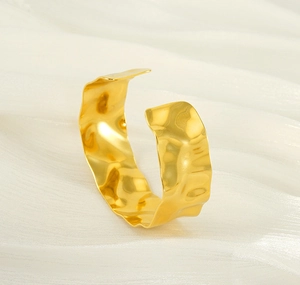 Detailed view of wide 18K gold C-shaped cuff bracelet with a hammered wavy texture
