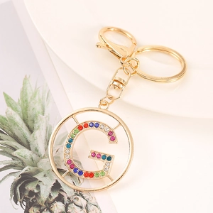 Detailed macro view of golden metal keychain featuring a colorful rhinestone letter G charm