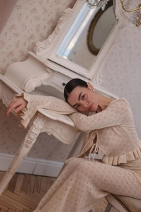 Detail of beige crochet knit set featuring lace-up cardigan with ruffled edges and hollow texture