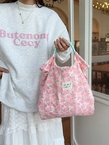 Pink floral quilted tote bag with light blue straps shown in a lifestyle setting