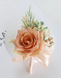 Detailed macro view of artificial champagne orange rose corsage with silk ribbon and gold berries