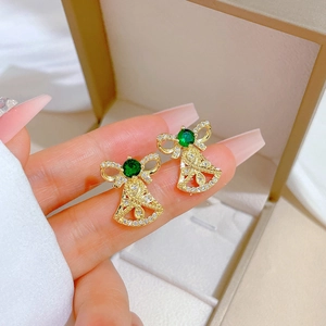 Detail of gold bell and green stone earrings with bowknot and pavé crystals