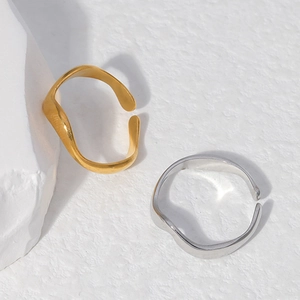 Detailed close-up of wave-shaped stainless steel rings in gold and silver finishes