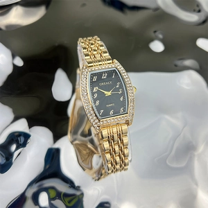 Macro shot of gold barrel-shaped watch dial with black face and crystal-set bezel