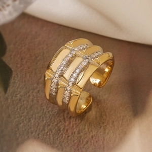 Macro shot of gold-plated wide ring with two rows of white zircons and wavy textures