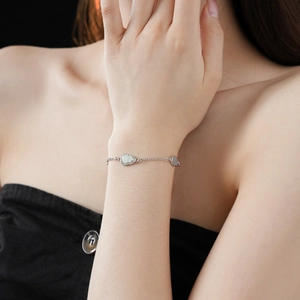 Detail of silver hollow gourd bracelet with zircon inlay on female wrist in elegant setting
