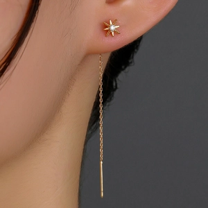 Macro shot of gold star-shaped threader earrings with sparkling cubic zirconia inlay