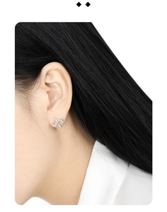 Close-up of a silver multi-layered bow earring worn on ear with high-quality metal finish