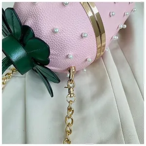Détail du sac fraise rose avec perles et décoration de couvercle en feuilles vertes