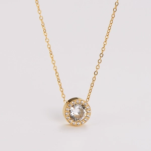 Close-up of golden necklace featuring a round pendant with sparkling clear crystals