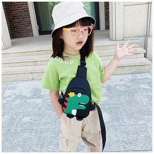 Close-up of cute green dinosaur print on a black chest bag for kids worn by a model