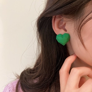 Minimalist green heart-shaped stud earrings with matte geometric finish on female model