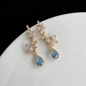 Détail de boucles d'oreilles papillon dorées avec pierres bleues et zircon brillant