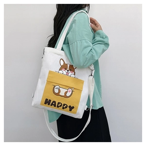 Detail of white canvas crossbody bag featuring a yellow front pocket with a Corgi print