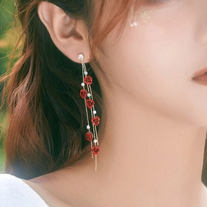 Close-up of elegant long red rose tassel earrings with white crystal rhinestones on a model