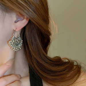 Detailed close-up of a silver ethnic style cluster earring worn by a model in warm light