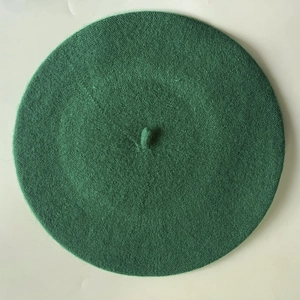 Top down close-up view of dark green cashmere beret showing knit texture and stem detail