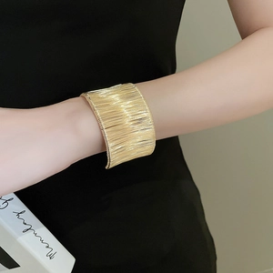 Macro detail of wide gold metal cuff bracelet with horizontal coiled wire texture finish