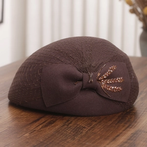 Detail of dark brown wool beret featuring a delicate mesh veil and sequined bow accent