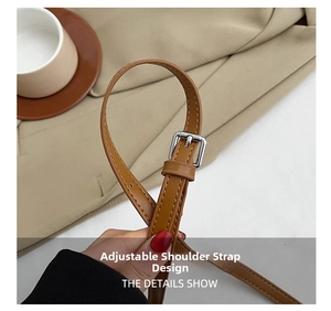 Détail d'une bandoulière en cuir marron réglable avec boucle argentée et surpiqûres
