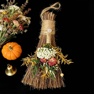 Handcrafted decorative holiday broom with dried flowers, pumpkin, and festive bell accents