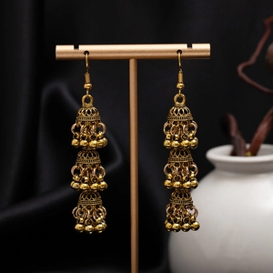 Macro shot of vintage gold Jhumka earrings with triple-layered bells and carved floral detail