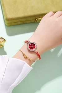 Detail of red rhinestone watch on model wrist with woven bracelet and quartz dial