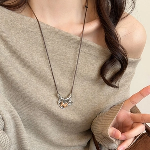 Detail of vintage wooden horse pendant on a long rope necklace against a knit sweater