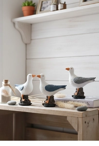 Detail of three resin seagull figurines on a shelf with Mediterranean coastal decor