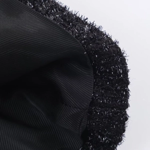 Makro-Detail des schwarzen Stoffes mit Metallic-Faden und Rippstrick-Futtertextur