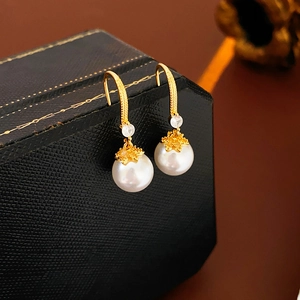 Detail of 14K gold plated pearl hook earrings with cubic zirconia and brushed metal finish