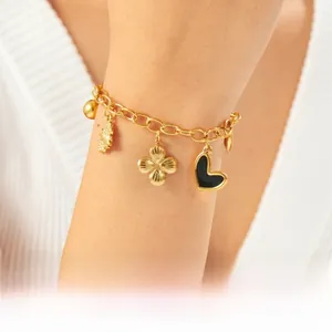 Detailed close-up of a gold-plated chain bracelet with black heart and clover charms