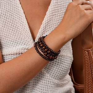 Close-up of bohemian multilayer dark brown wood bead bracelet worn on a female wrist
