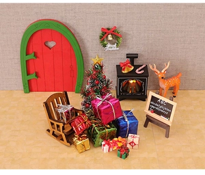 Miniature Christmas scene with a red fairy door, small Xmas tree, and tiny gift box props