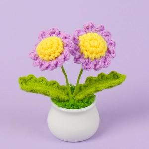 Detail of handmade crochet purple daisies in a white ceramic pot on purple background