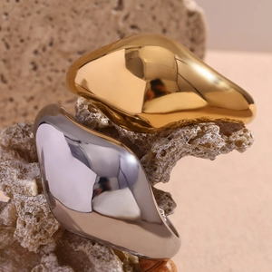 Polished 18K gold and silver minimalist curved bangle on textured rock background