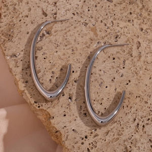 Macro shot of silver minimalist V-shaped hollow hoop earrings on a stone background