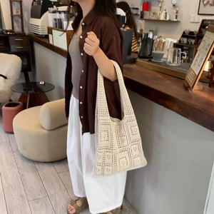 Detailed view of white hollow-out knit shoulder bag with geometric crochet pattern