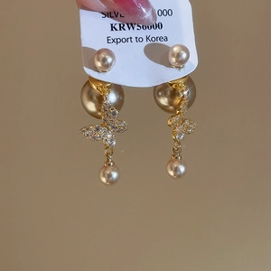 Detail showing gold butterfly earrings with cubic zirconia and dangling pearls