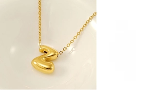 Detailed macro view of an 18K gold bubble letter Z pendant on a delicate chain