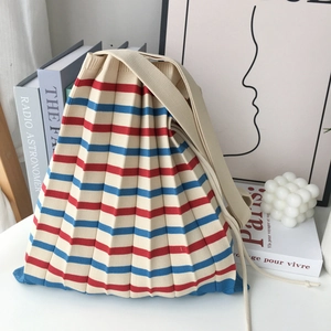 Beige pleated knit tote bag with red and blue stripes and a long shoulder strap